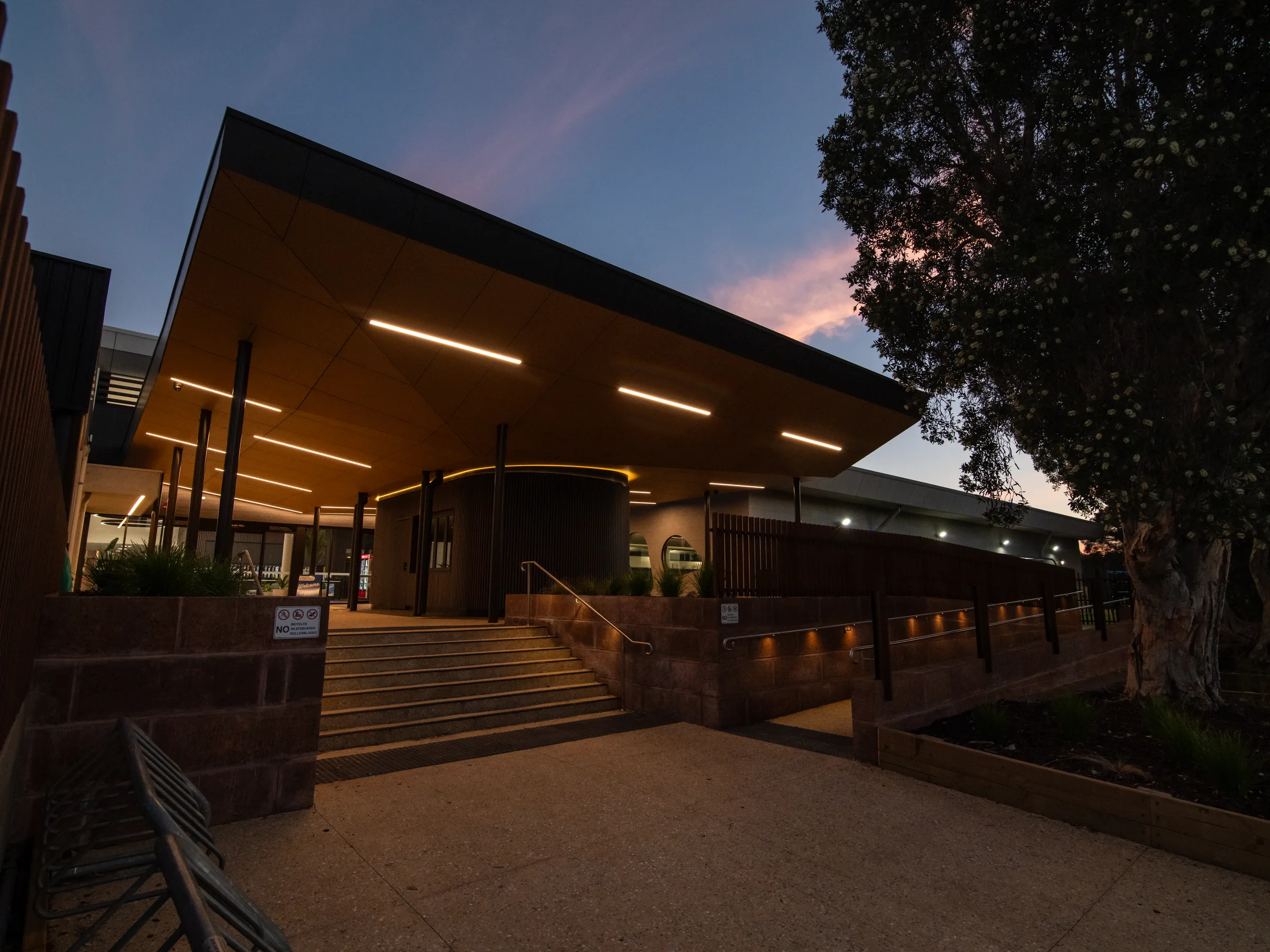 The folded roof of an aquatic centre at dusk, warm light washing the soffit
