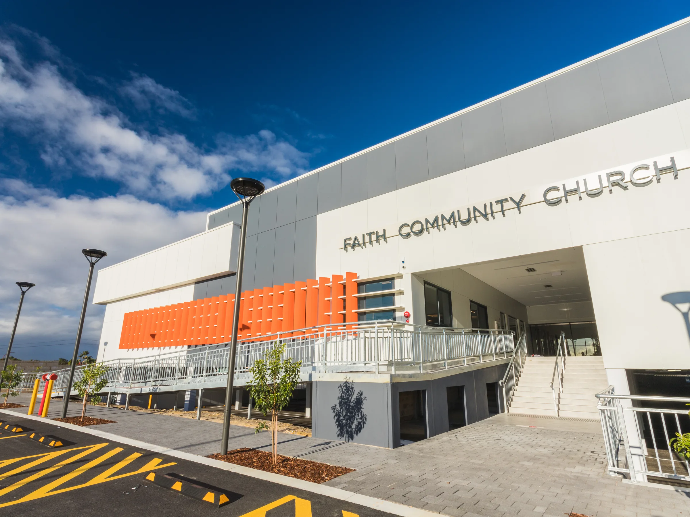 A white and orange church facade carrying its name beneath a clear sky
